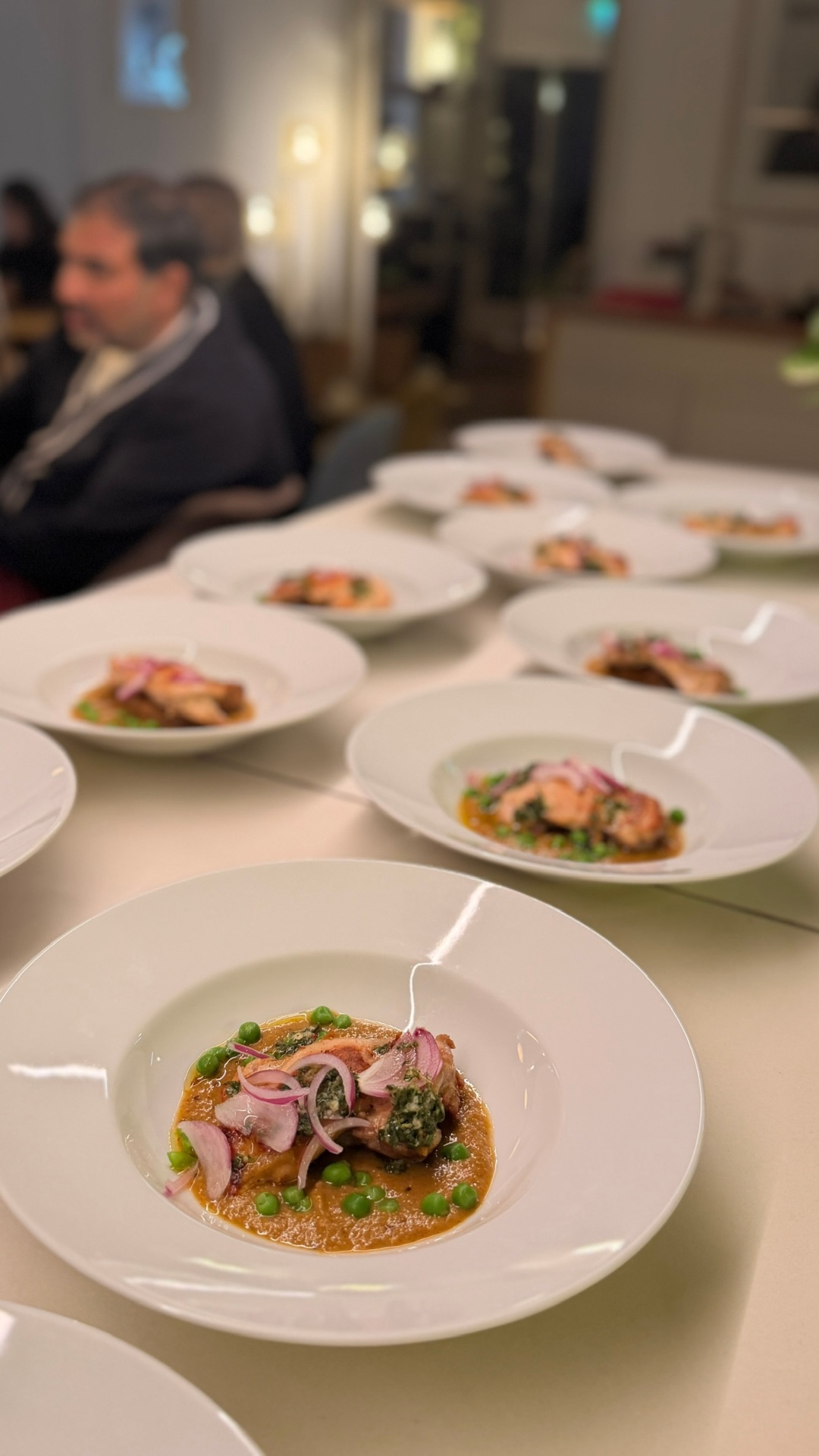 Rows of chicken courses in a rich orange sauce ready for service
